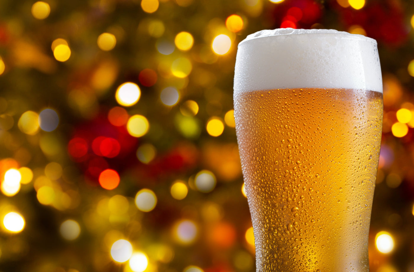 Glass of beer with a festive background featuring blurred lights and colors.